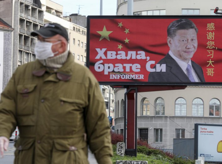A man wearing a protective mask passes by a billboard depicting Chinese President Xi Jinping as the spread of the coronavirus disease (COVID-19) continues in Belgrade, Serbia, April 1, 2020. The text on the billboard reads "Thanks, brother Xi". Picture ta